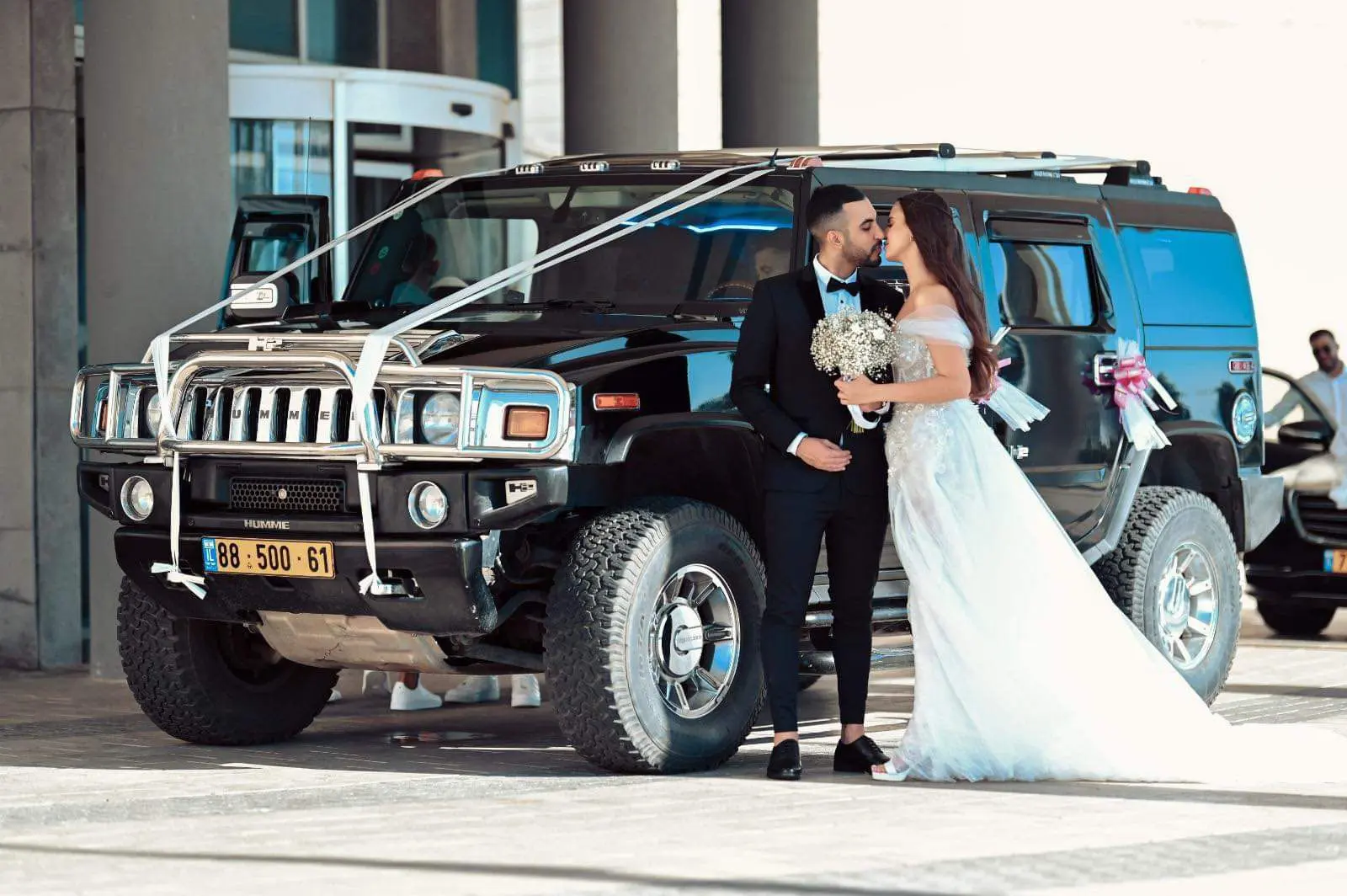 חתן וכלה ליד ה-Hummer השחור המקושט לחתונה